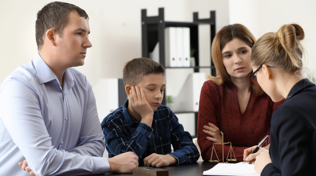 A family sits in the office of a lawyer who examines a document.