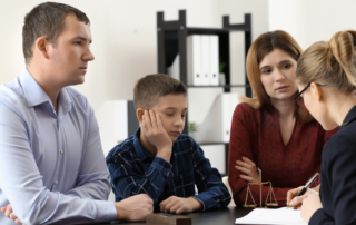 A family sits in the office of a lawyer who examines a document.