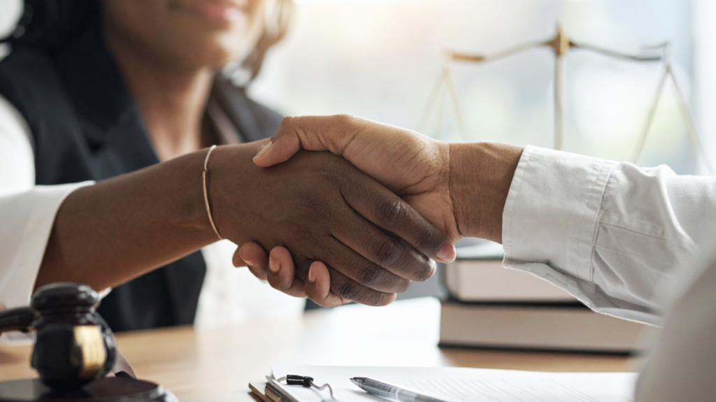 A close up of a lawyer shaking hands with a prospective client at a consultation.