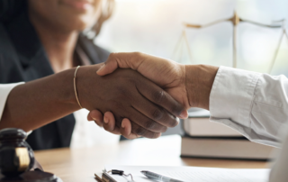 A close up of a lawyer shaking hands with a prospective client at a consultation.
