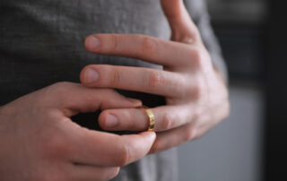 A man removes a gold wedding ring from his hand after a divorce.