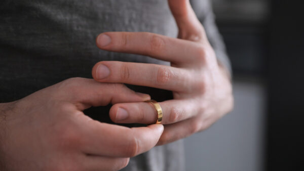 A man removes a gold wedding ring from his hand after a divorce.