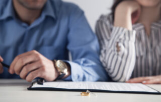 A man and woman sit at a table with divorce papers and their marriage rings.